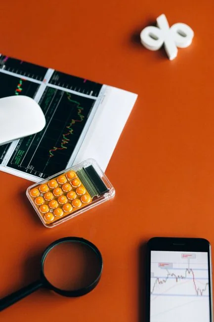 Magnifying glass and colored pencils on financial trend graphs highlighting sales growth.